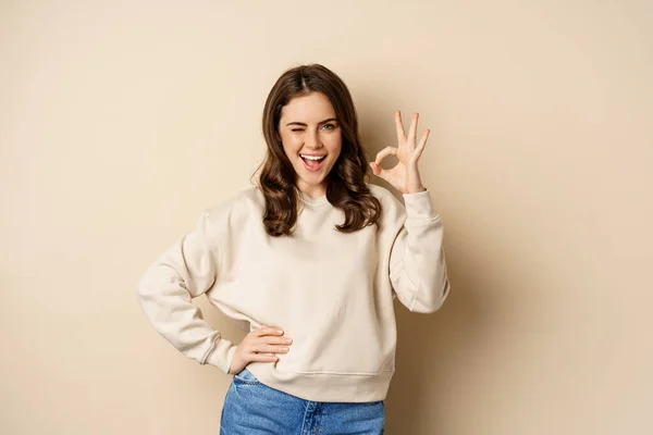 Excellent. Smiling beautiful woman showing okay, ok zero sign, approve smth good, praising and complimenting, beige background — Fotografia de Stock