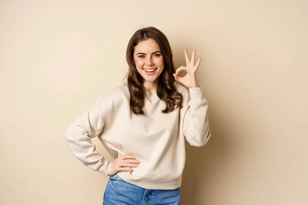 Excellent. Smiling beautiful woman showing okay, ok zero sign, approve smth good, praising and complimenting, beige background — Foto de Stock