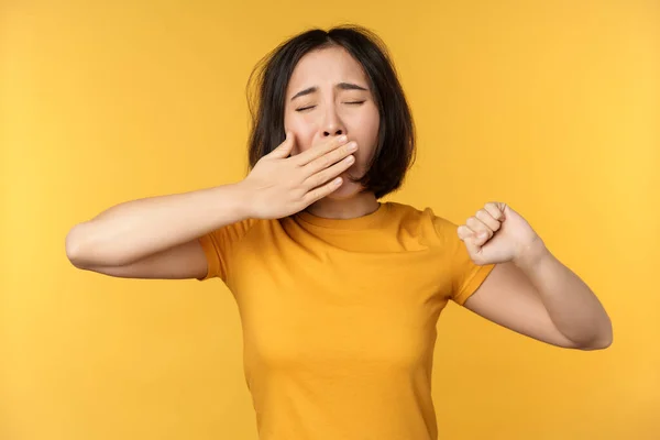 Зображення молодої студентки азіатської дівчини, позіхання, відчуття втоми, стоячи сором'язливий жовтий фон — стокове фото