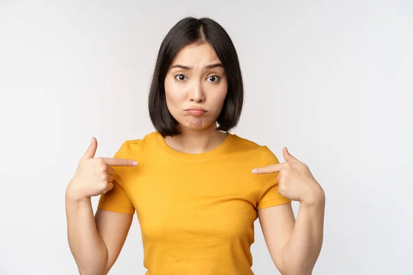 Confundida mujer asiática señalándose a sí misma, mirando en incredulidad, de pie sobre fondo blanco — Foto de Stock