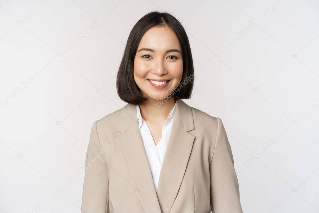 Portrait of successful businesswoman in suit, smiling and looking like professional at camera, white background.