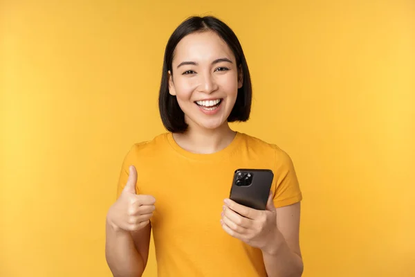 Щаслива Усміхнена Азіатська Дівчина Тримає Мобільний Телефон Показує Великі Пальці — стокове фото