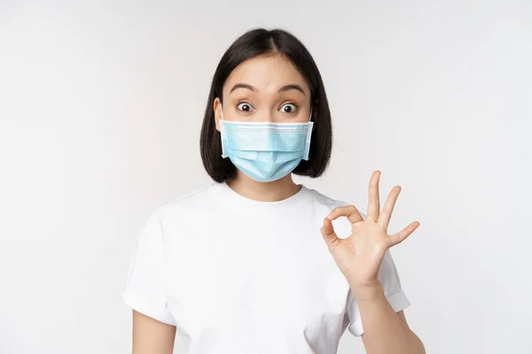 Covid 医療と医療の概念 白い背景の上に立って サインを見て 医療用マスクで印象的なアジアの女性 — ストック写真