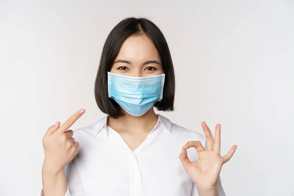 Porträtt Asiatisk Flicka Medicinsk Mask Visar Okej Tecken Och Pekar — Stockfoto