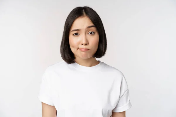 白のTシャツ 笑顔で若いアジアのブルネットの女性のイメージと白の背景に対して立って 躊躇し 疑いを持って見てください スペースのコピー — ストック写真