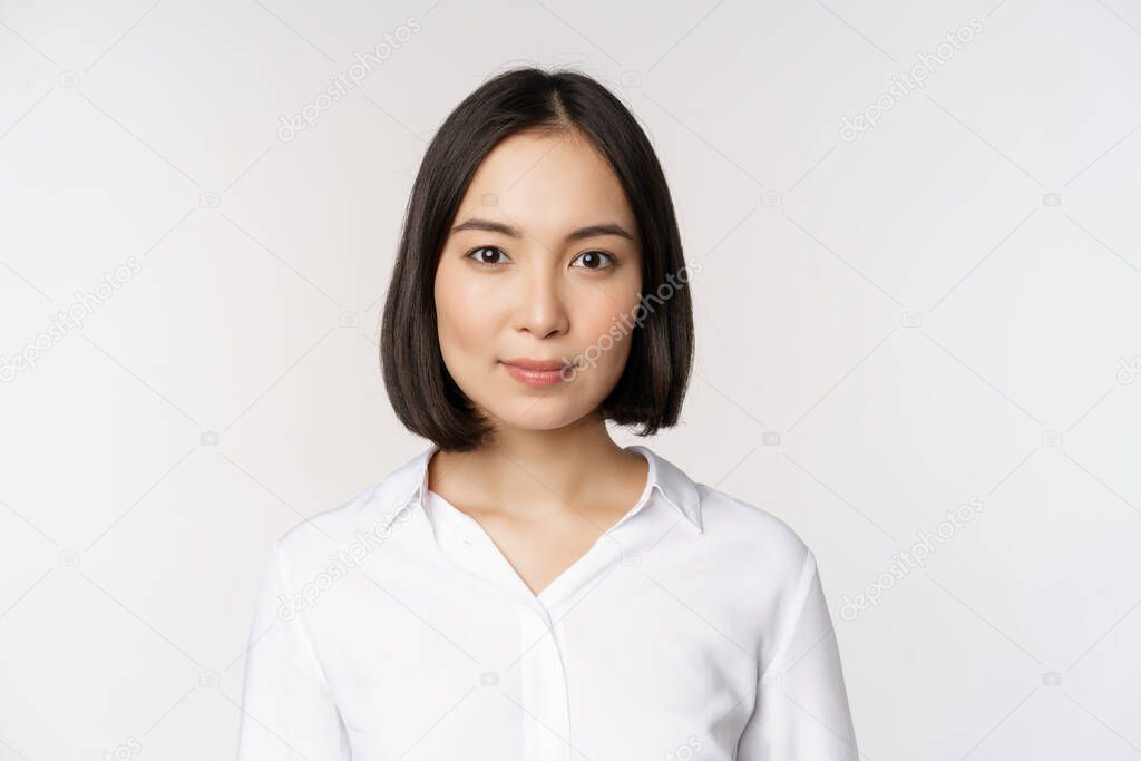 Close up portrait of korean young asian woman, professional, looking confident and assertive at camera, white background. Business people concept