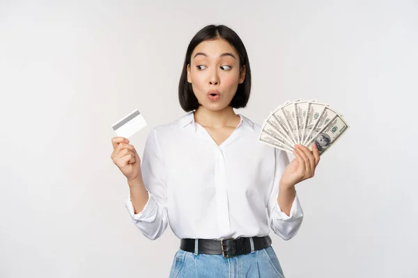 Spännande Koreansk Tjej Tittar Kreditkort Håller Pengar Kontanter Poserar Mot — Stockfoto