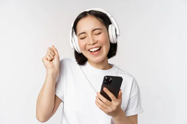 Hermosa Chica Asiática Moderna Escuchando Música Auriculares Sosteniendo Teléfono Móvil — Foto de Stock