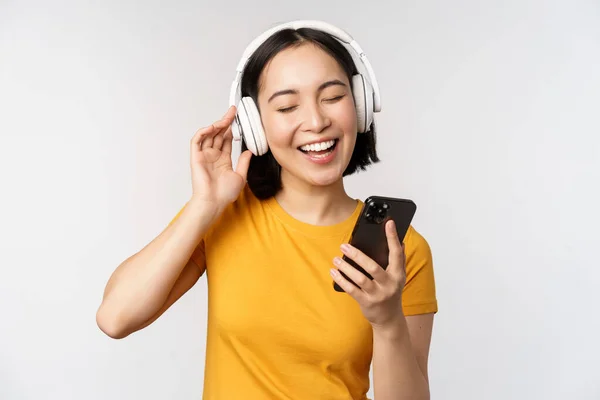 Linda Chica Japonesa Los Auriculares Mirando Teléfono Móvil Sonriendo Utilizando —  Fotos de Stock