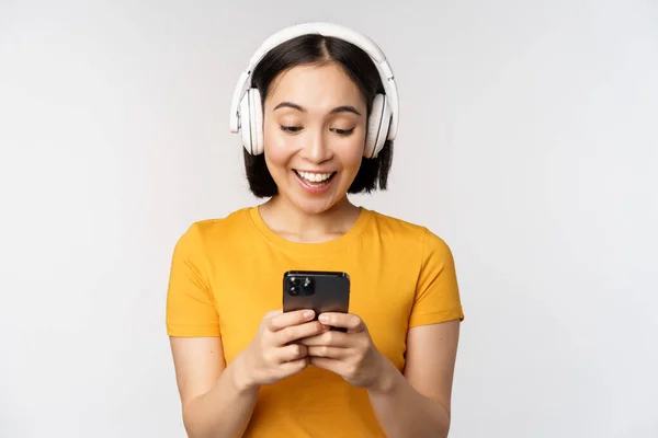 Ładna Japońska Dziewczyna Słuchawkach Patrząc Telefon Komórkowy Uśmiechnięty Pomocą Aplikacji — Zdjęcie stockowe