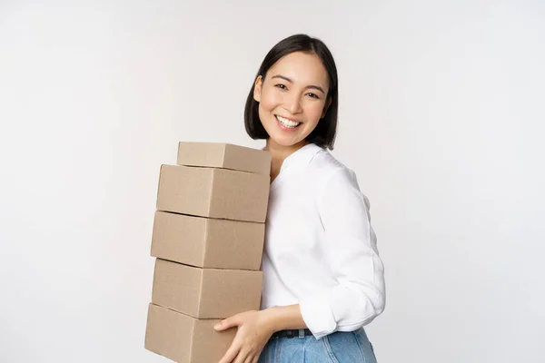 Retrato de jovem asiático mulher segurando caixas, transportar mercadorias de entrega. Coreano empresário feminino montar ordem, pé voer fundo branco — Fotografia de Stock