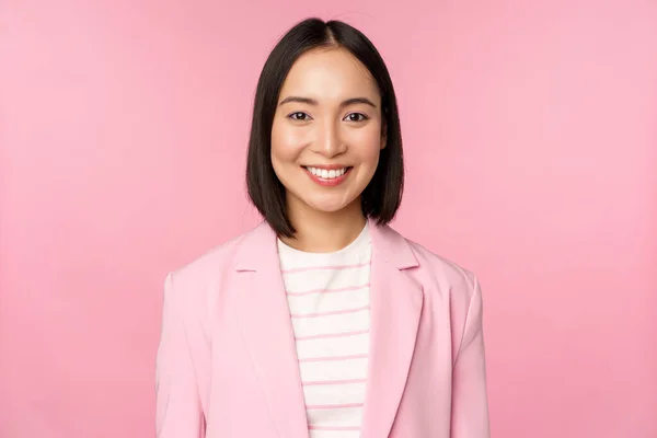 Jovens profissionais. Sorrindo asiática empresária, vendedora de terno olhando confiante para a câmera, posando contra fundo rosa — Fotografia de Stock