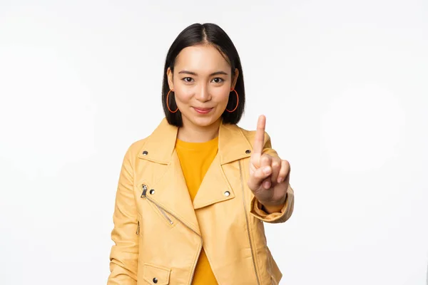 Regel nummer ett. Självsäker leende asiatisk kvinna visar pekfingret, stoppa, förbjuda gest, ogilla smth, står över vit bakgrund — Stockfoto