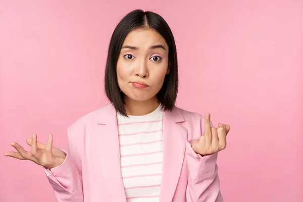 Retrato de joven mujer de negocios asiática, vendedora encogiéndose de hombros y buscando confundido, despistado de smth, de pie sobre fondo rosa —  Fotos de Stock