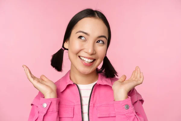 Έννοια φροντίδας δέρματος και κοσμετολογίας. Όμορφο κορίτσι από την Ασία χαμογελώντας και γελώντας, δείχνει καθαρό υγιές δέρμα του προσώπου, ποζάροντας σε ροζ φόντο — Φωτογραφία Αρχείου