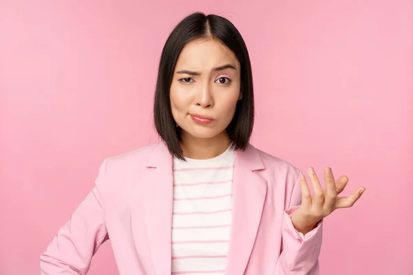 Portrait de femme asiatique en colère en costume, les poings serrés et l'air furieux, indigné de smth mauvais, debout sur fond rose — Photo