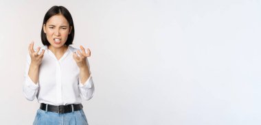 Image of angry pissed off woman shaking from anger, clench hands and grimacing furious, annoyed and outrated, standing over white background