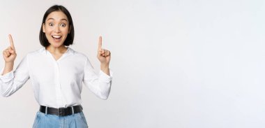 Hevesli iş kadını, Asyalı kadın manken parmaklarını havaya kaldırıyor ve gülümsüyor, duyuru yapıyor, üstünde logo afişi olan beyaz bir arka plan var.