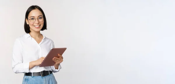 Image de jeune femme asiatique, travailleur de l'entreprise dans des lunettes, souriant et tenant tablette numérique, debout sur fond blanc — Photo