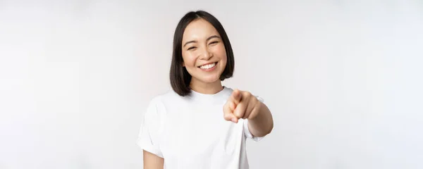하얀 치아를 가진 행복 한 동양 여성 이 카메라를 향해 손가락 질하며 백인 배경 위에 서서 축하하는 모습 — 스톡 사진