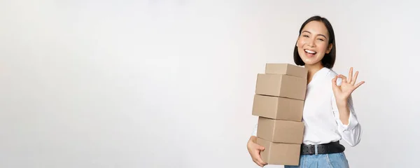 Porträt der schönen glücklichen Frau tragen Kisten mit Aufträgen. Geschäftsfrau mit Carry-Delivery und Okay-Zeichen, weißer Hintergrund — Stockfoto