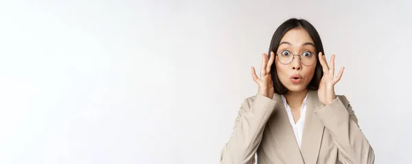 Ritratto di donna d'affari asiatica in occhiali, guardando sorpreso stupito davanti alla macchina fotografica, in piedi in abito su sfondo bianco — Foto Stock