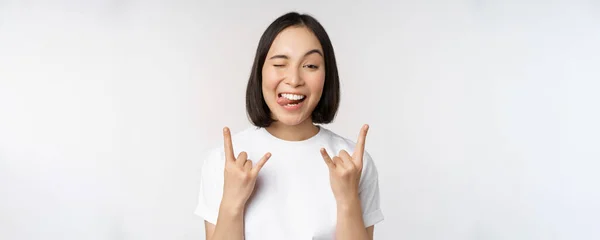 Chica asiática descarada gritando, disfrutando de concierto o festival, mostrando rock on, cartel de heavy metal, divirtiéndose, de pie sobre fondo blanco — Foto de Stock