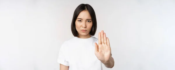 Imagem de menina asiática mostrando parar, proibir smth, estender um braço para mostrar proibindo, gesto tabu, de pé em tshirt sobre fundo branco — Fotografia de Stock