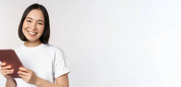 笑顔アジアの女の子とともにデジタルタブレット,見て幸せと笑い,白い背景の上にtシャツにポーズ — ストック写真