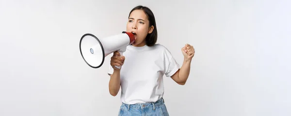 Chica asiática gritando al megáfono, joven activista protestando, usando altavoz, de pie sobre fondo blanco — Foto de Stock