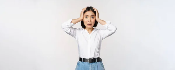 Kép a megdöbbent ideges ázsiai nő pánik, kézen fogva a fejét, és aggasztó, álló frusztrált és ijedt fehér háttér — Stock Fotó
