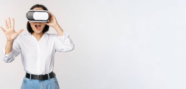 Vr sohbet. Asyalı kız sanal gerçeklik gözlükleriyle merhaba diyor, coşkuyla gülümsüyor, iletişim konsepti ve gelecek teknolojisi, beyaz arka plan