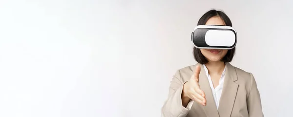 在Vr聊天。戴着虚拟现实眼镜的亚洲女商人，与商业伙伴握手，问候某人，站在白色的背景上 — 图库照片
