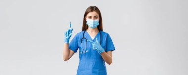 Covid-19, virüsün önlenmesi, sağlık, sağlık çalışanları ve karantina konsepti. Mavi önlüklü, tıbbi maskeli, Coronavirus aşısı olan ciddi bir kadın hemşire ya da doktor.