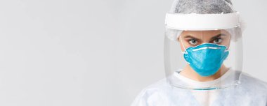Covid-19, virüsü önleme, sağlık çalışanları ve karantina konsepti. Kişisel koruyucu kostüm, solunum cihazı ve yüz kalkanı takmış ciddi, kararlı bir doktor ya da hemşireye yakın çekim.