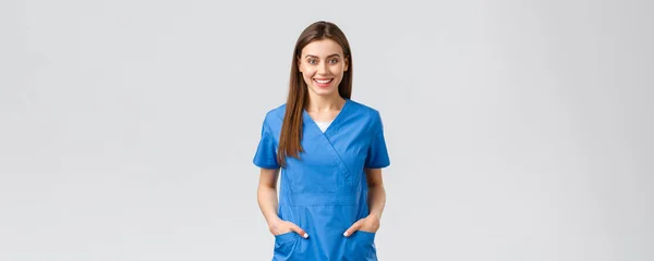 Travailleurs de la santé, prévenir le virus, concept d'assurance et de médecine. Joyeux sourire beau médecin, infirmière en blouse bleue, stagiaire à l'hôpital rester positif, debout fond gris — Photo