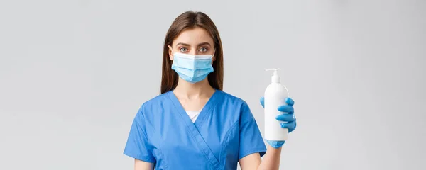 Covid-19, mencegah virus, kesehatan, pekerja kesehatan dan konsep karantina. Pekerja medis, perawat atau dokter berbaju biru dan topeng medis, menunjukkan pembersih tangan atau sabun — Stok Foto