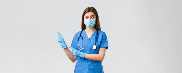 Covid-19 、ウイルス、健康、医療従事者の概念を防止します。青い頭皮で懐疑的な女性看護師,医療用マスクと手袋,疑わしい見て、左上隅を指して — ストック写真