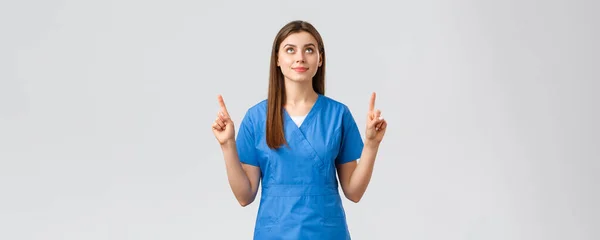 医療従事者,ウイルスを防止します, covid-19テストスクリーニング,医学の概念.若い才能のある医者、青い頭の女性看護師、指を指してサインやバナーを見て、灰色の背景 — ストック写真
