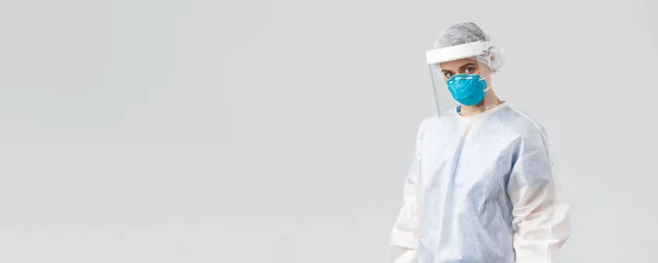 Covid-19, prevence viru, zdraví, zdravotnických pracovníků a koncepce karantény. Vážná, odhodlaná lékařka, ošetřovatelka v ochranném obleku PPE, obličejová maska a štít, hledící kamera, zachraňující pacienty — Stock fotografie