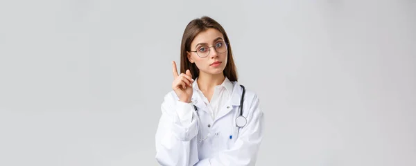 Gesundheitspersonal, Medizin, Versicherung und Covid-19-Pandemiekonzept. Smart professionelle Ärztin in weißen Peelings und Brille, haben Idee, Vorschlag, heben Zeigefinger Eureka Zeichen — Stockfoto