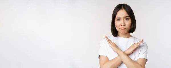 Retrato de mujer coreana asiática mostrando stop, gesto de prohibición, mostrando el signo de cruz del brazo, de pie en camiseta sobre fondo blanco — Foto de Stock