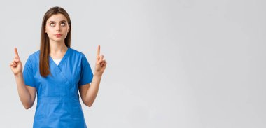 Sağlık çalışanları, virüsü önleyin, covid-19 test taraması, tıp konsepti. Endişeli, ciddi ve odaklanmış kadın doktor ya da mavi önlüklü hemşire, işaret ediyor ve pankarta bakıyor.