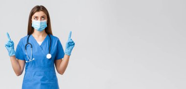 Covid-19, virüsün önlenmesi, sağlık, sağlık çalışanları ve karantina konsepti. Meraklı kadın doktor ya da hemşire mavi önlüklü, tıbbi maske okuyan, işaret eden