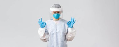 Covid-19, virüsün önlenmesi, sağlık, sağlık çalışanları ve karantina konsepti. Koruyucu ekipmanda kendine güvenen doktor ya da hemşire PPE, solunum cihazı, tıbbi eldiven tamam gösteriyor.