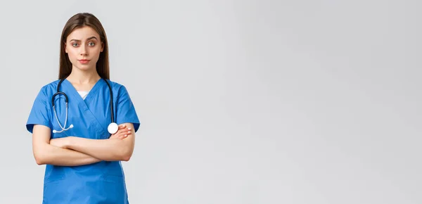 Travailleurs de la santé, prévenir le virus, concept d'assurance et de médecine. Infirmière sceptique ou médecin en blouse bleue, poitrine croisée et regard impatient, mécontentement souriant — Photo