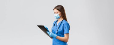 Covid-19, virüsün önlenmesi, sağlık, sağlık çalışanları ve karantina konsepti. Normal hasta kontrolü sırasında profesyonel kadın hemşire ya da doktor, panoya bilgi yazıyorlar.