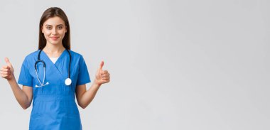 Sağlık çalışanları, virüsü, sigortayı ve ilaç konseptini engelleyin. Destekleyici profesyonel hemşire ya da doktor mavi önlüklü, steteskoplu, onaylı baş parmağını göster, gülümse.