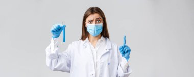 Covid-19, virüsü önleme, sağlık çalışanları ve karantina konsepti. Kişisel koruyucu ekipman, tıbbi maske ve eldiven giyen, Coronavirus aşısı örneği gösteren, emin değilim.