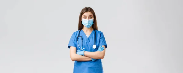 Covid-19, prevenire virus, salute, operatori sanitari e concetto di quarantena. Divertente medico o infermiera in camice blu con stetoscopio e dispositivi di protezione individuale sembrano incuriositi — Foto Stock